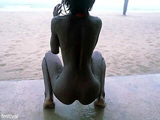 Smal svart tjej dansar naken på stranden visar tight midja och tuttar